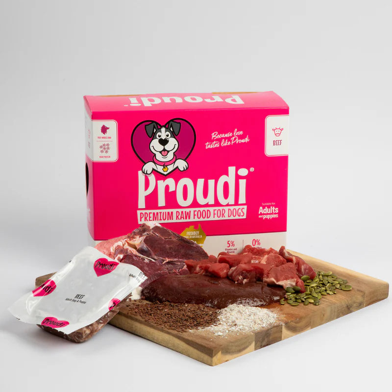 Proudi premium raw food for dogs packaging with ingredients on a wooden board.