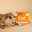 Proudi dog food box with a dachshund and raw dog food ingredients on a wooden board.