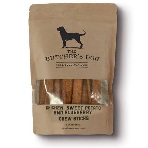 A package of 'The Butcher's Dog' Chicken, Sweet Potato, and Blueberry Chew Sticks for dogs, shown in a brown kraft paper stand-up pouch with a clear window displaying the brown chew sticks inside.